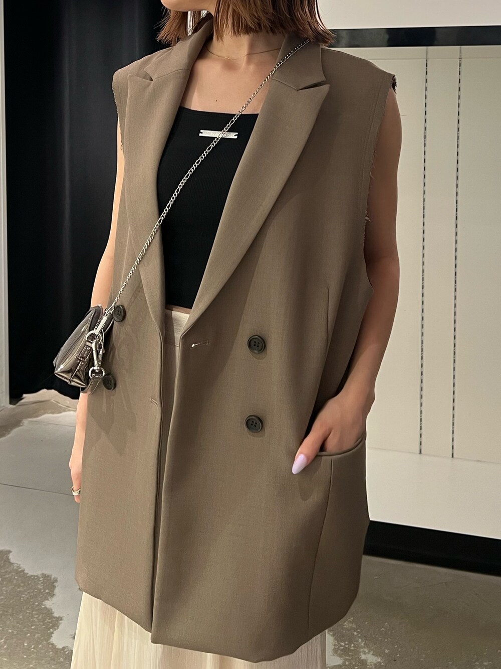 ブラック系のサンダル、ホワイト系のスカート、ゴールド系のショルダーバッグを着用したレディースの夏コーディネートの7枚目の写真