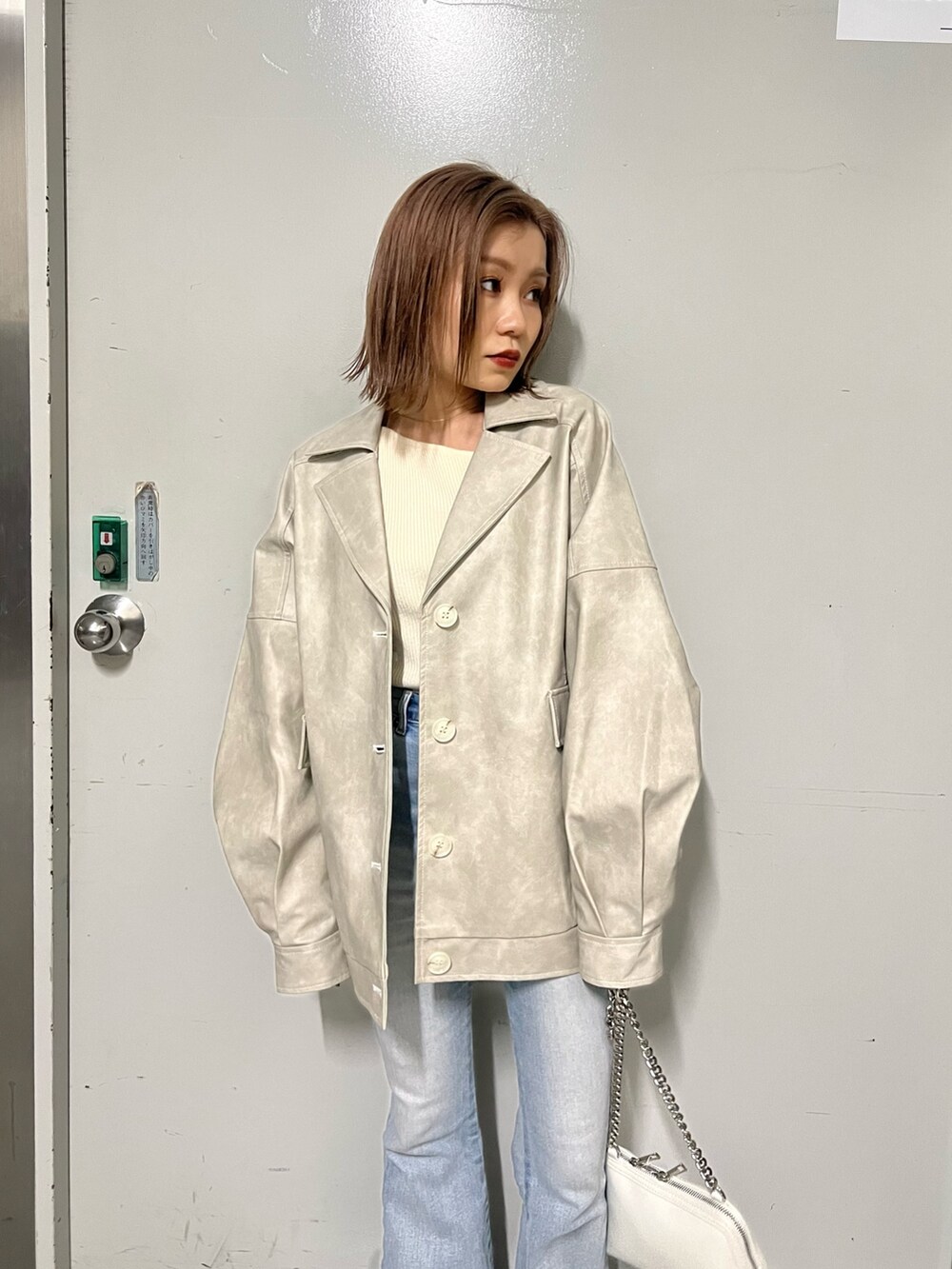 ホワイト系のブルゾン、ホワイト系のニット/セーター、ホワイト系のハンドバッグを着用したレディースの冬コーディネートの5枚目の写真