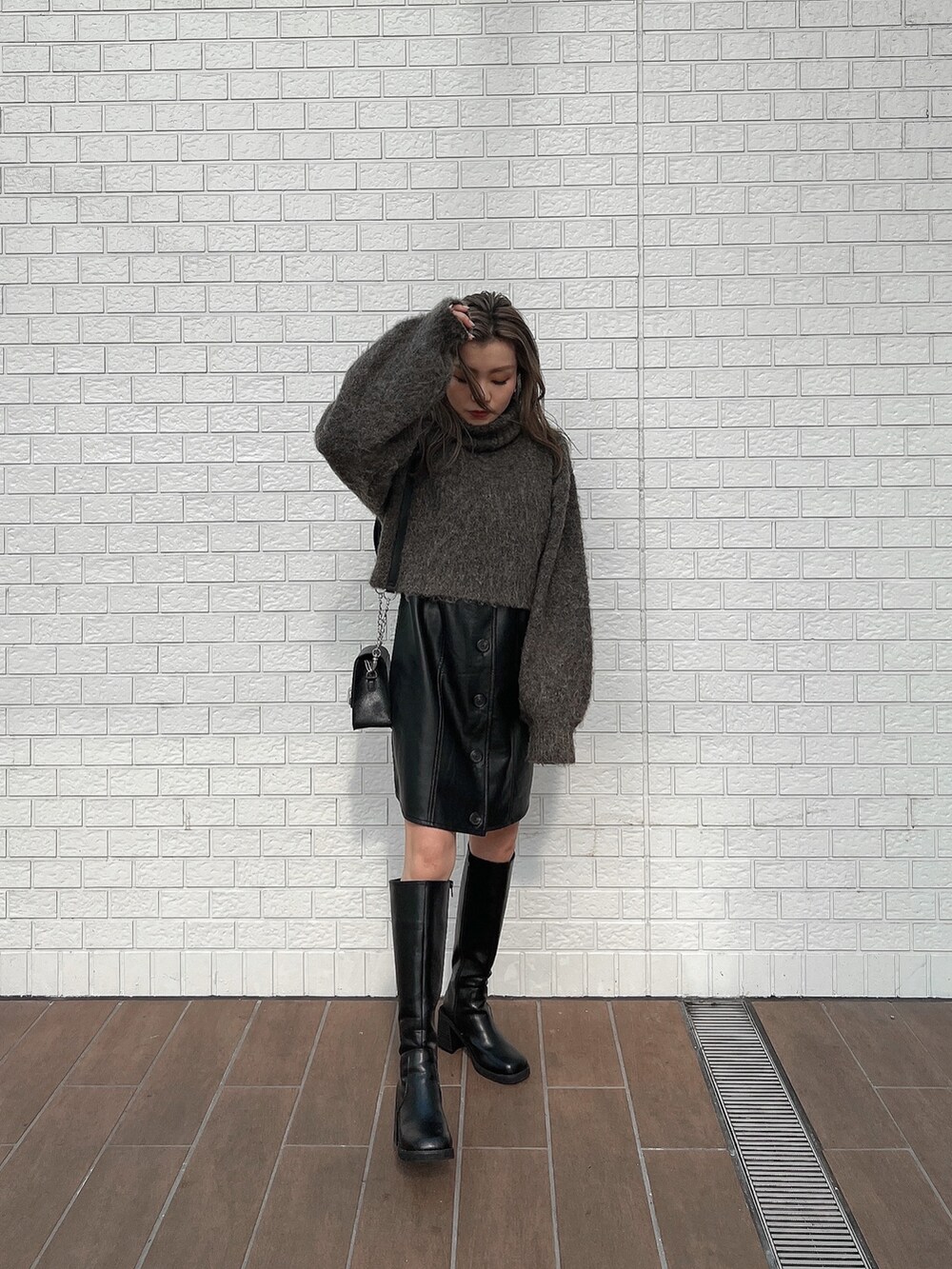 ブラック系のワンピース、ブラック系のブーツ、ブラウン系のニット/セーターを着用したレディースの秋コーディネートの2枚目の写真