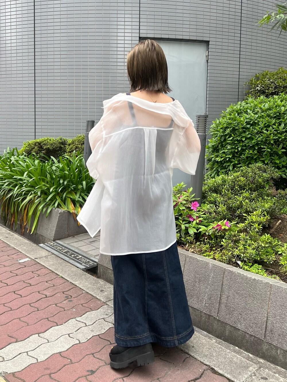 ホワイト系のシャツ/ブラウス、グレー系のニット/セーター、ブルー系のデニムスカートを着用したレディースの春コーディネートの3枚目の写真