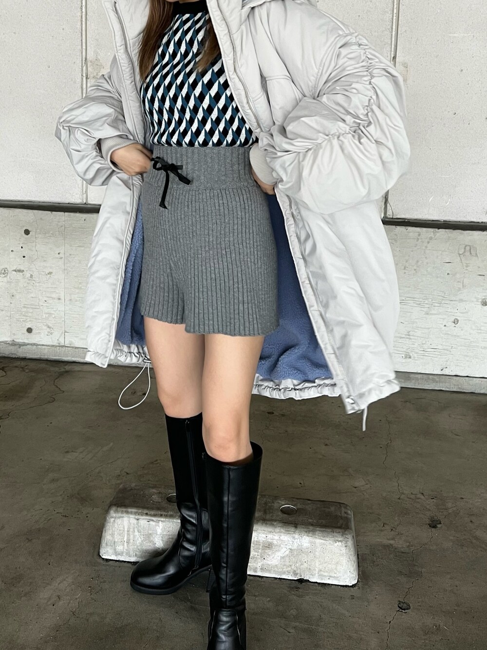 ホワイト系のブルゾン、ブラック系のニット/セーター、グレー系のスウェットパンツを着用したレディースの冬コーディネートの4枚目の写真