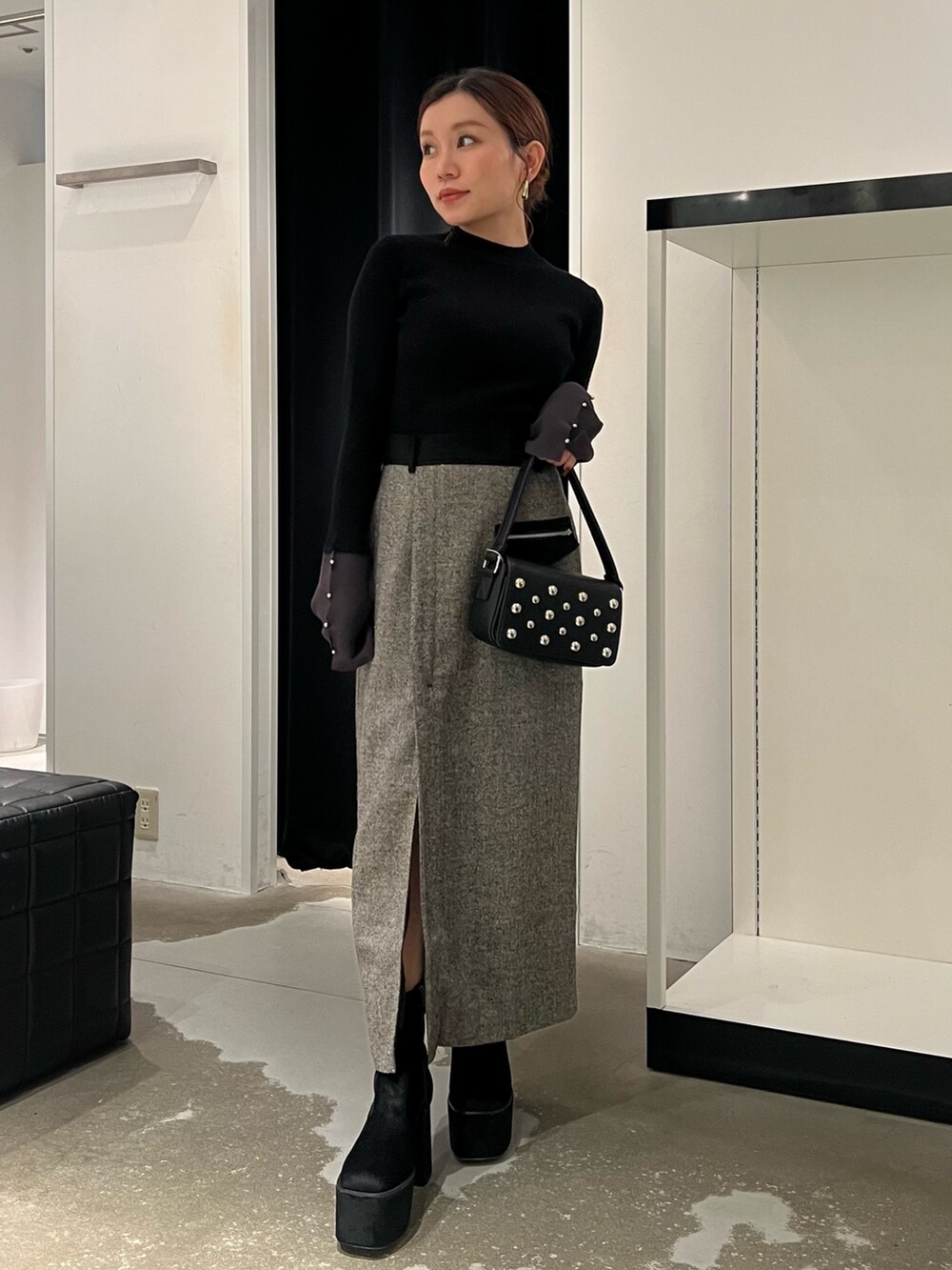 ブラック系のニット/セーター、ブラック系のスカート、ブラック系のブーツを着用したレディースの秋コーディネートの4枚目の写真