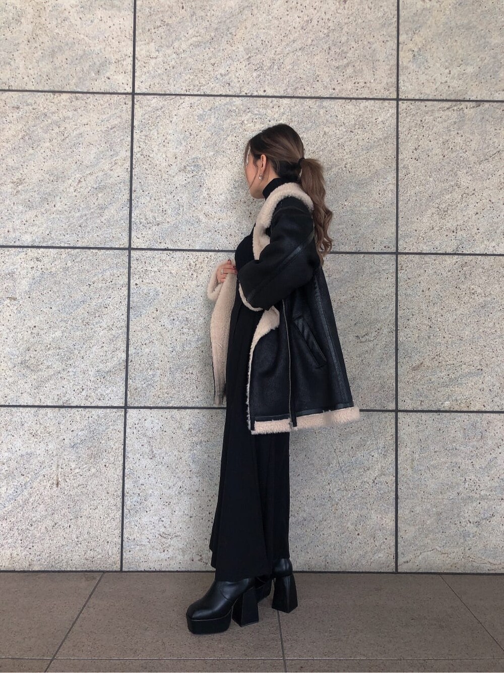 ブラック系のスカート、ブラック系のブルゾン、ブラック系のブーツを着用したレディースの秋コーディネートの4枚目の写真