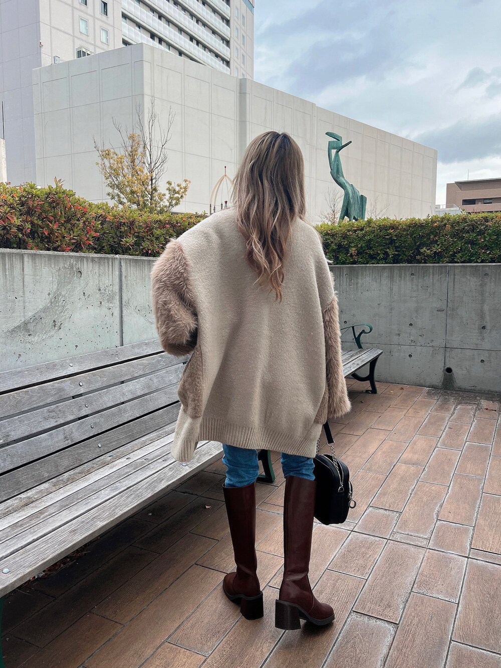 ホワイト系のニット/セーター、ベージュ系のカーディガン/ボレロ、ブラウン系のブーツを着用したレディースの冬コーディネートの3枚目の写真