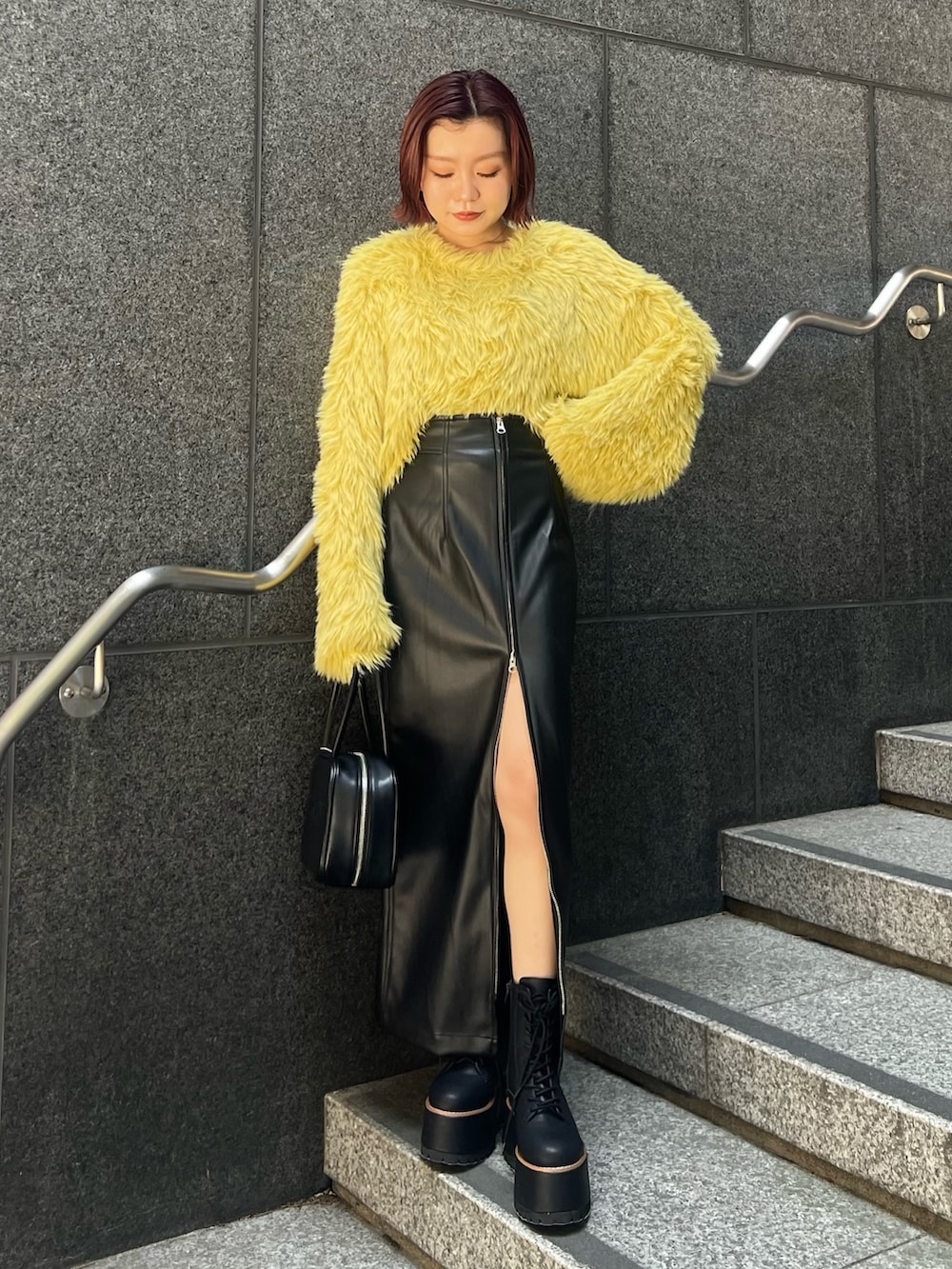 イエロー系のニット/セーター、ブラック系のスカート、ブラック系のブーツを着用したレディースの秋コーディネートの4枚目の写真