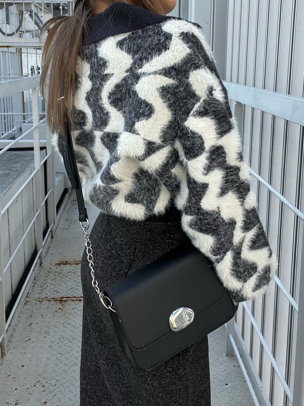 ブラック系のニット/セーター、ブラック系のスカート、ブラック系のショルダーバッグを着用したレディースの秋コーディネートの7枚目の写真