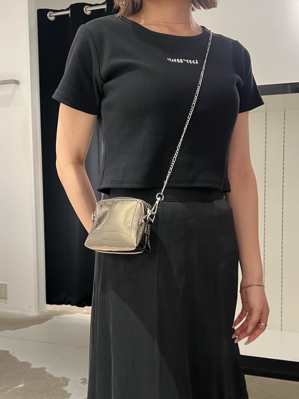 ブラック系のTシャツ/カットソー、ブラック系のスカート、ゴールド系のショルダーバッグを着用したレディースの夏コーディネートの6枚目の写真