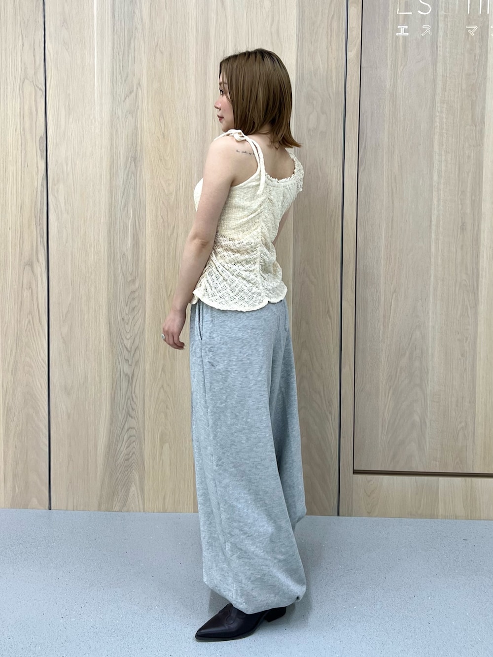グレー系のスウェットパンツ、ホワイト系のタンクトップ、ブラウン系のブーツを着用したレディースの春コーディネートの2枚目の写真