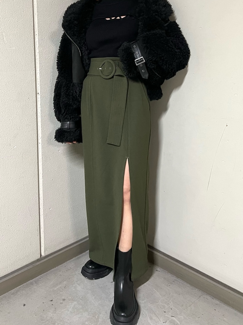 ブラック系のムートンコート、ブラック系のニット/セーター、グリーン系のスカートを着用したレディースの冬コーディネートの6枚目の写真