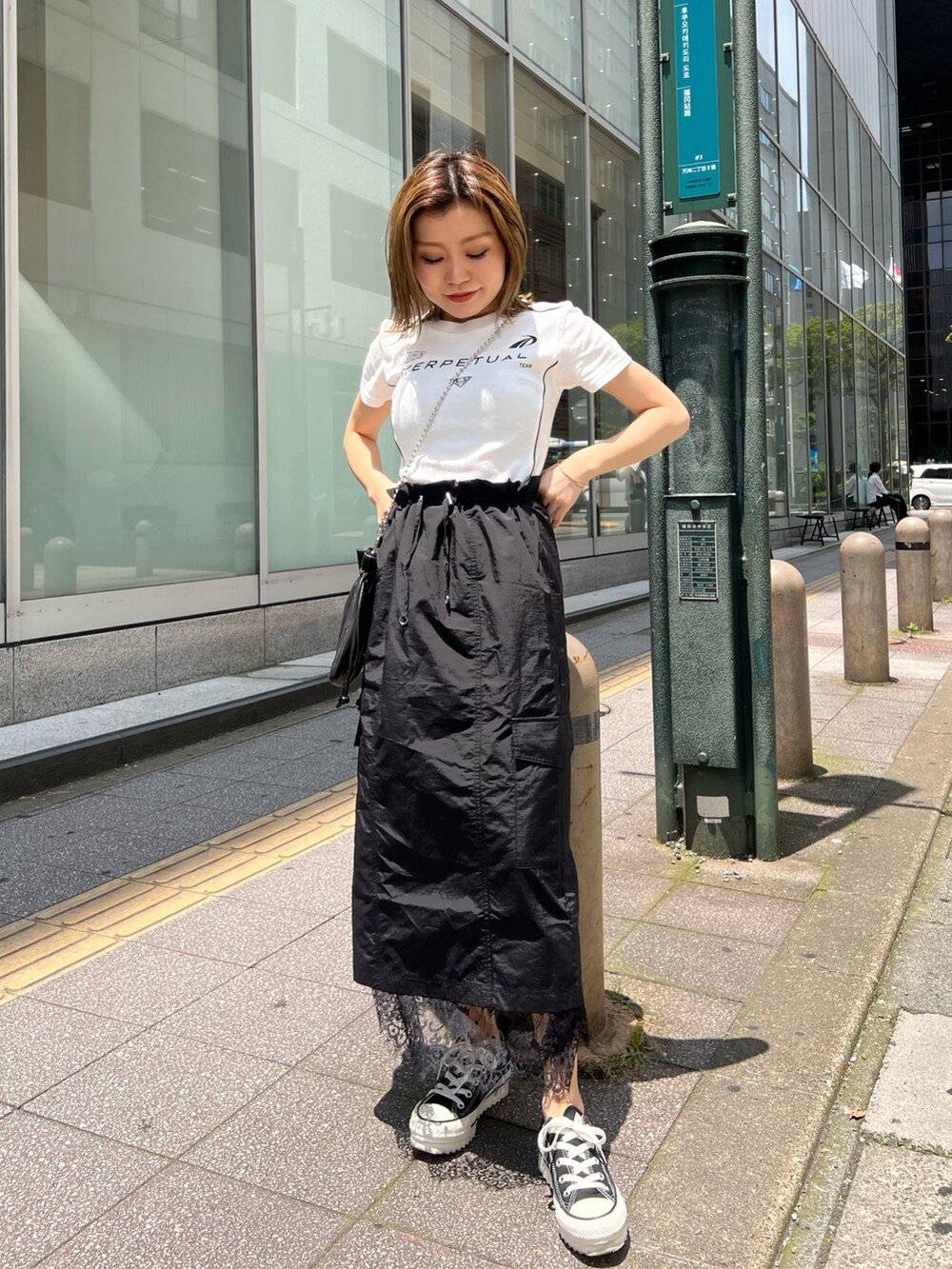 ブラック系のスカート、ブラック系のショルダーバッグ、ホワイト系のTシャツ/カットソーを着用したレディースの夏コーディネートの4枚目の写真