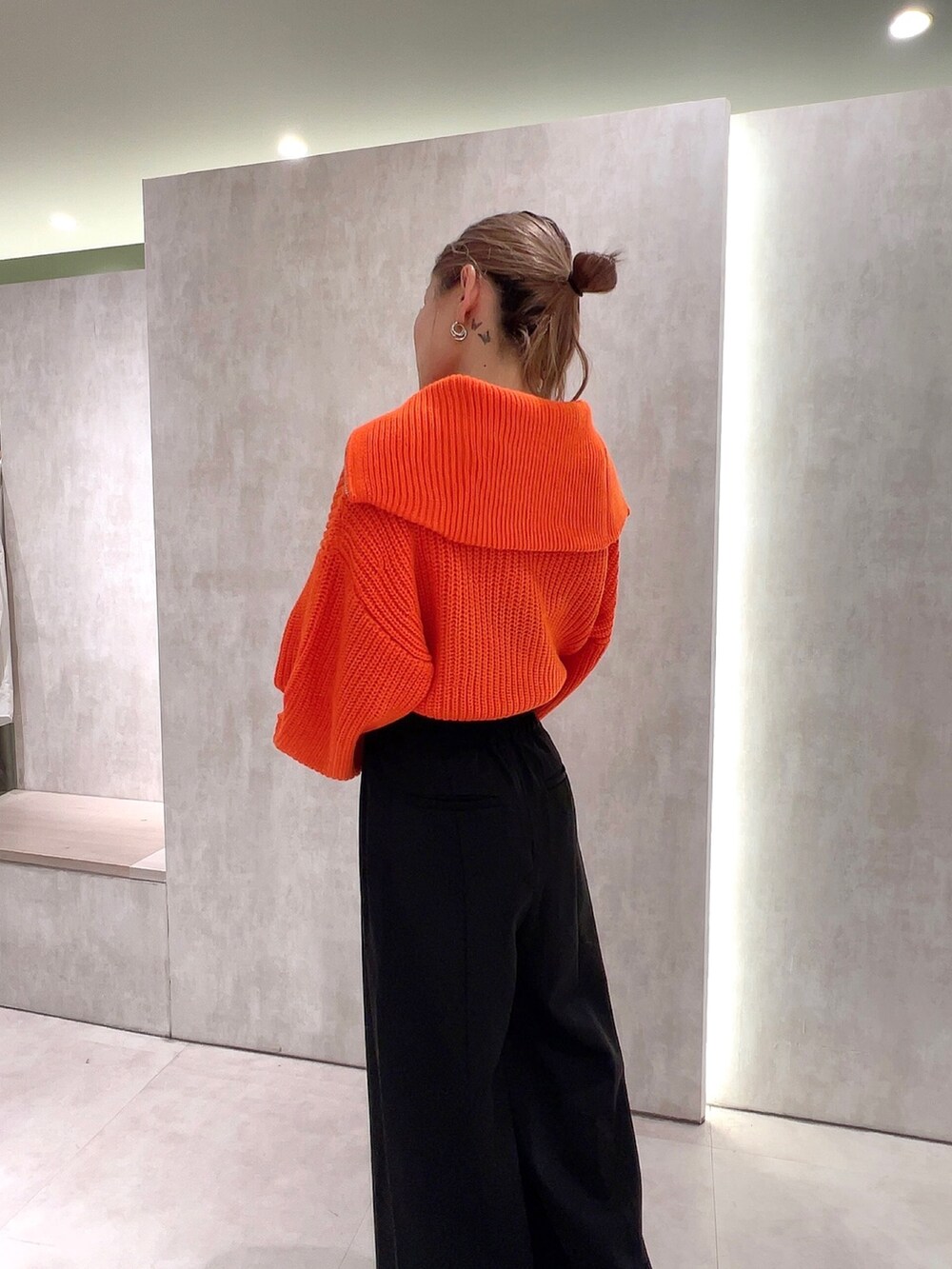 ブラック系のスラックス、オレンジ系のニット/セーター、ブラック系のムートンコートを着用したレディースの冬コーディネートの8枚目の写真