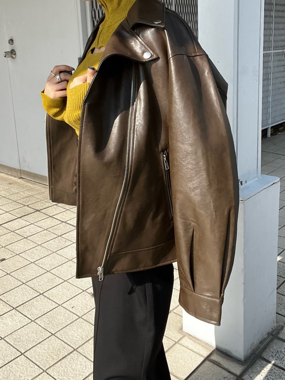 ブラウン系のライダースジャケット、ブラック系のスラックス、ブラック系のローファーを着用したレディースの秋コーディネートの7枚目の写真