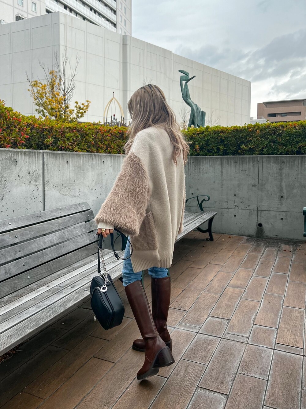 ホワイト系のニット/セーター、ベージュ系のカーディガン/ボレロ、ブラウン系のブーツを着用したレディースの冬コーディネートの2枚目の写真