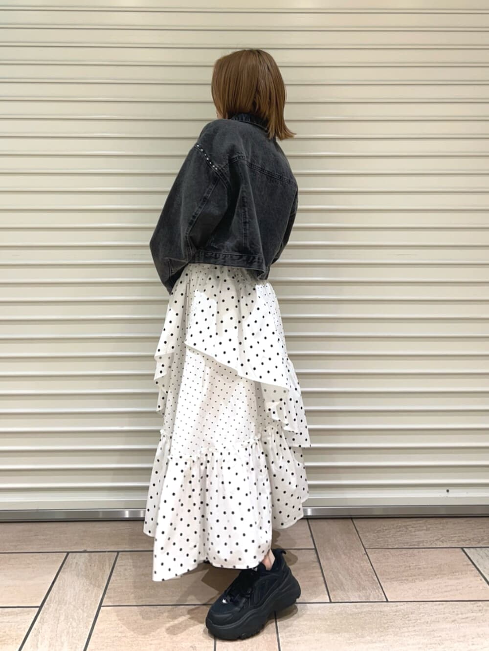 イエロー系のTシャツ/カットソー、ブラック系のデニムジャケット、ホワイト系のスカートを着用したレディースの春コーディネートの2枚目の写真