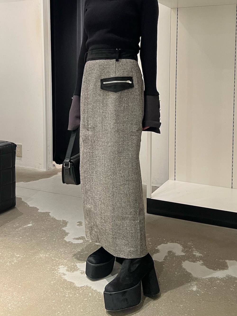 ブラック系のニット/セーター、ブラック系のスカート、ブラック系のブーツを着用したレディースの秋コーディネートの6枚目の写真