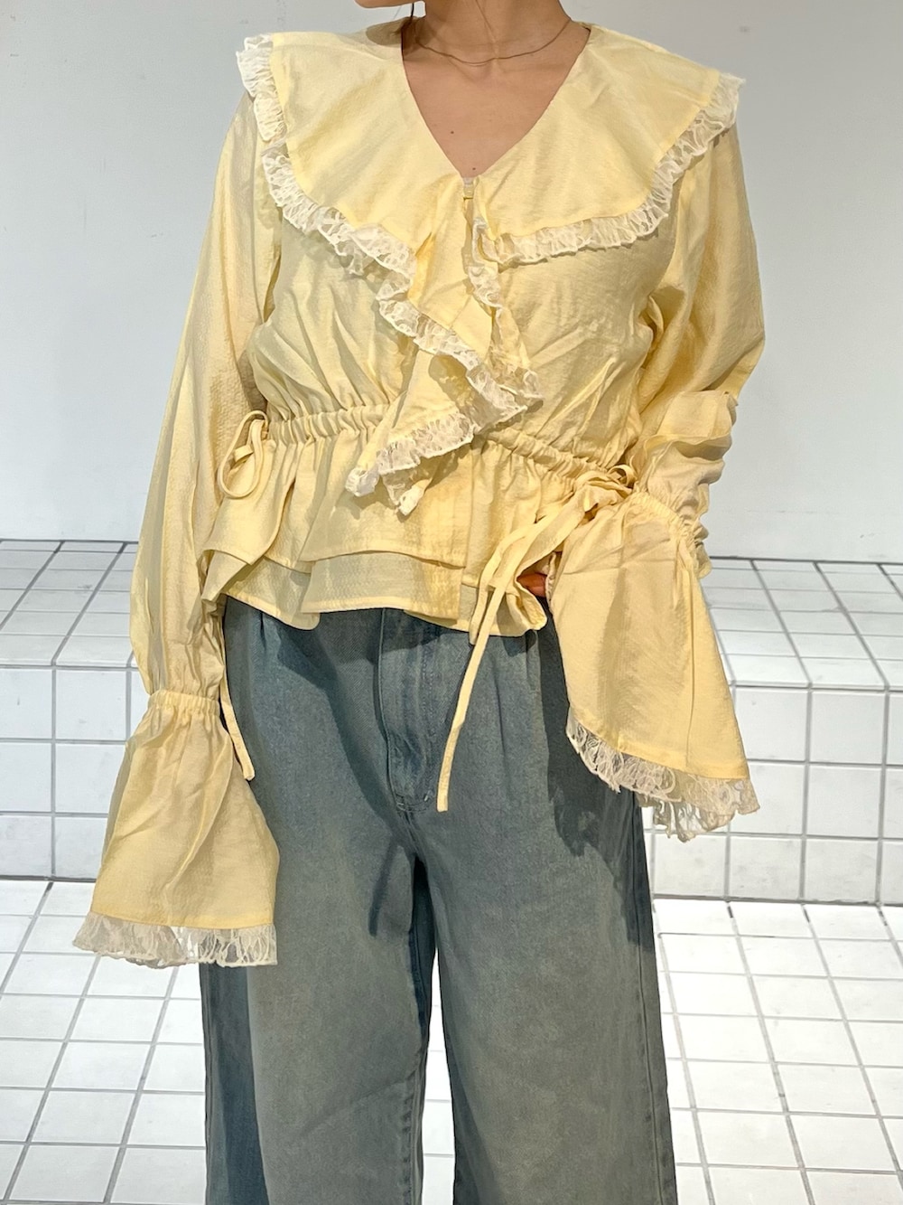 ブルー系のデニムパンツ、イエロー系のシャツ/ブラウス、ブラック系のサンダルを着用したレディースの春コーディネートの6枚目の写真