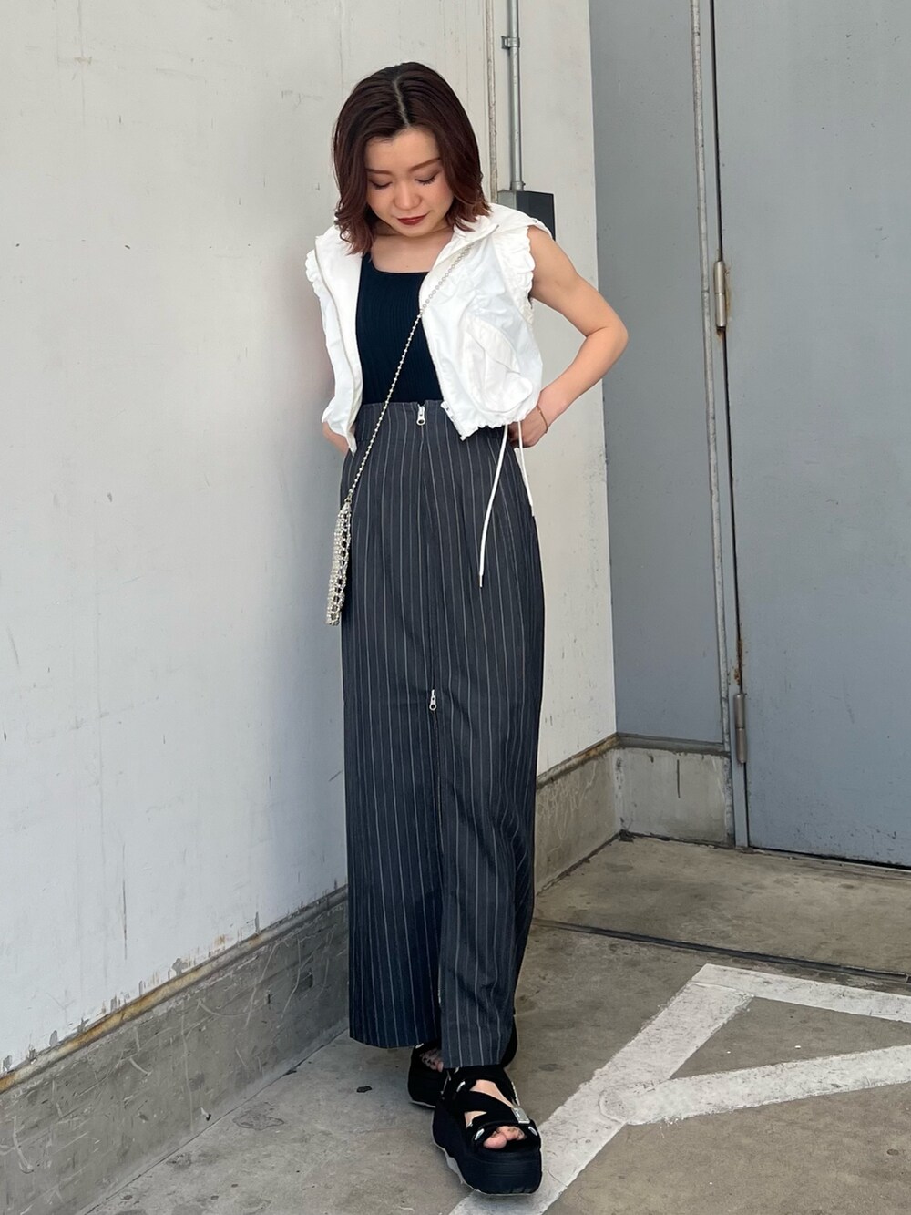 ホワイト系のベスト、ブラック系のタンクトップ、グレー系のスカートを着用したレディースの春コーディネートの4枚目の写真