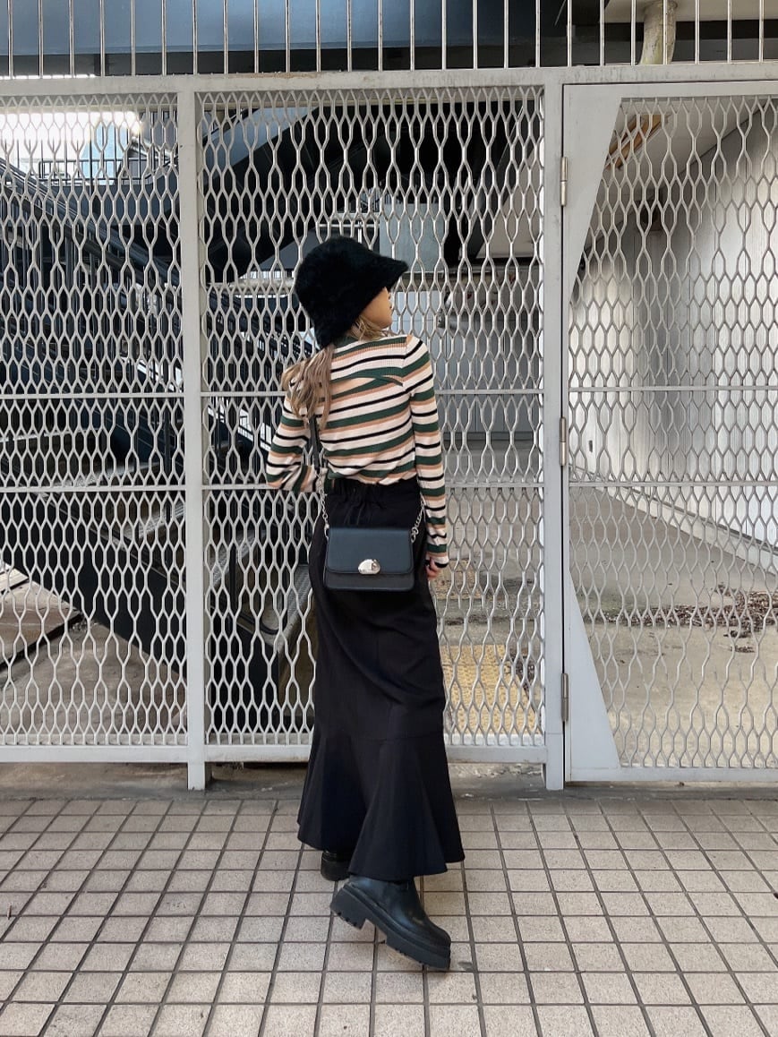 ブラック系のブーツ、ブラック系のショルダーバッグ、ブラック系のスカートを着用したレディースの秋コーディネートの2枚目の写真