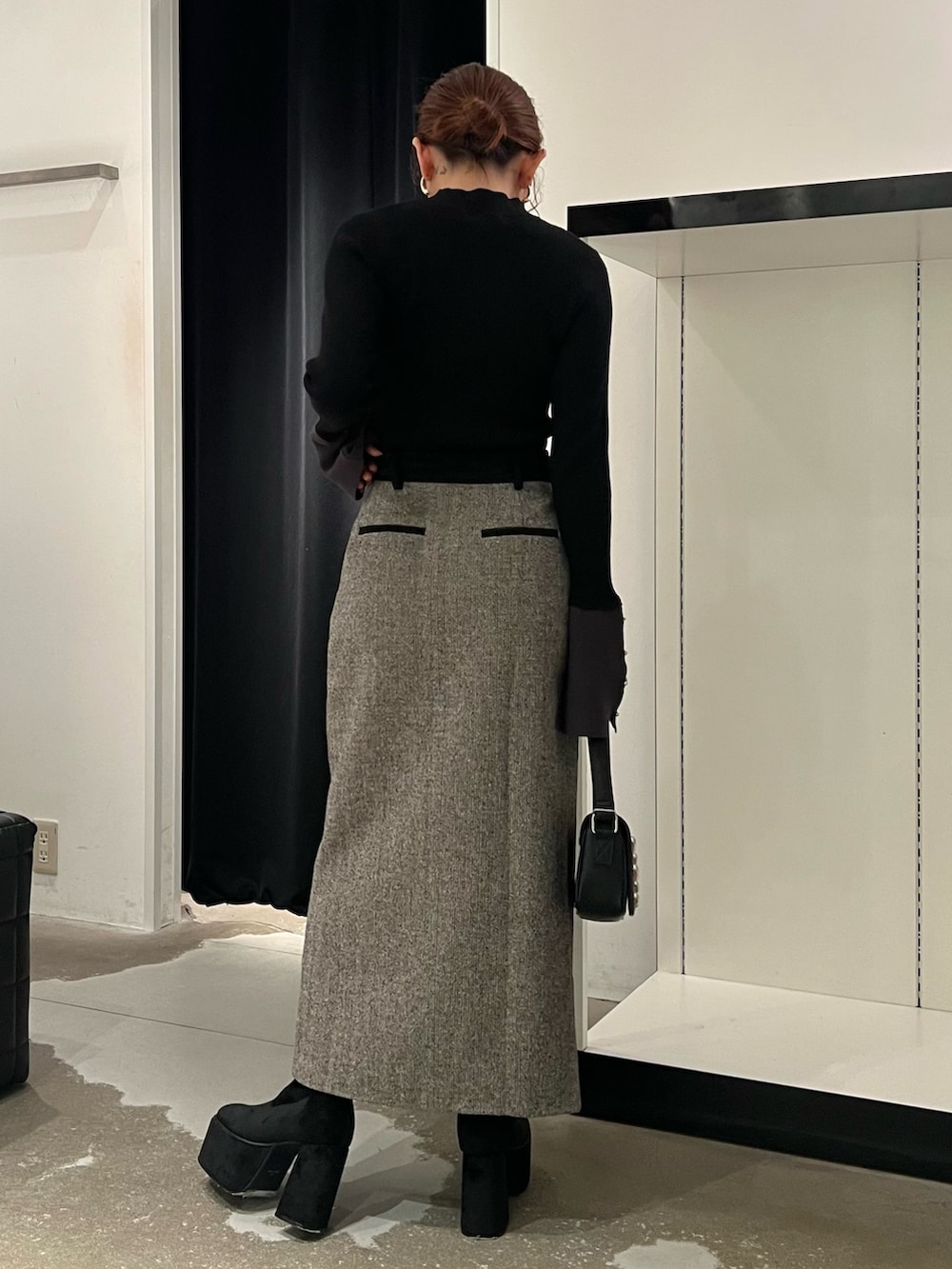 ブラック系のニット/セーター、ブラック系のスカート、ブラック系のブーツを着用したレディースの秋コーディネートの3枚目の写真