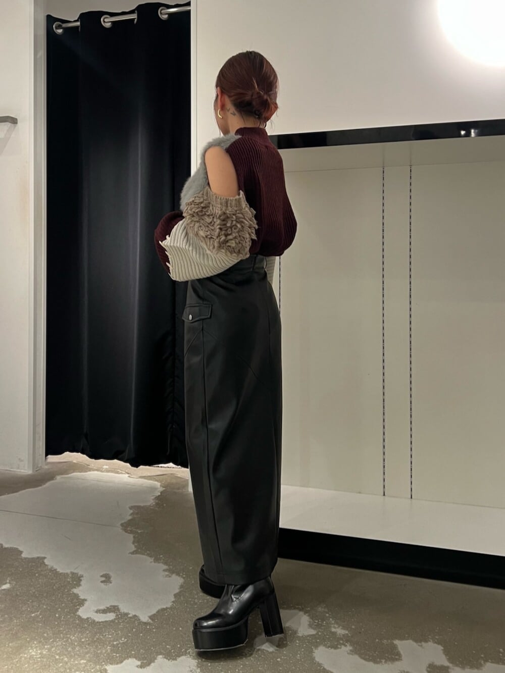 ブラック系のブーツ、レッド系のニット/セーター、ブラック系のスカートを着用したレディースの秋コーディネートの2枚目の写真