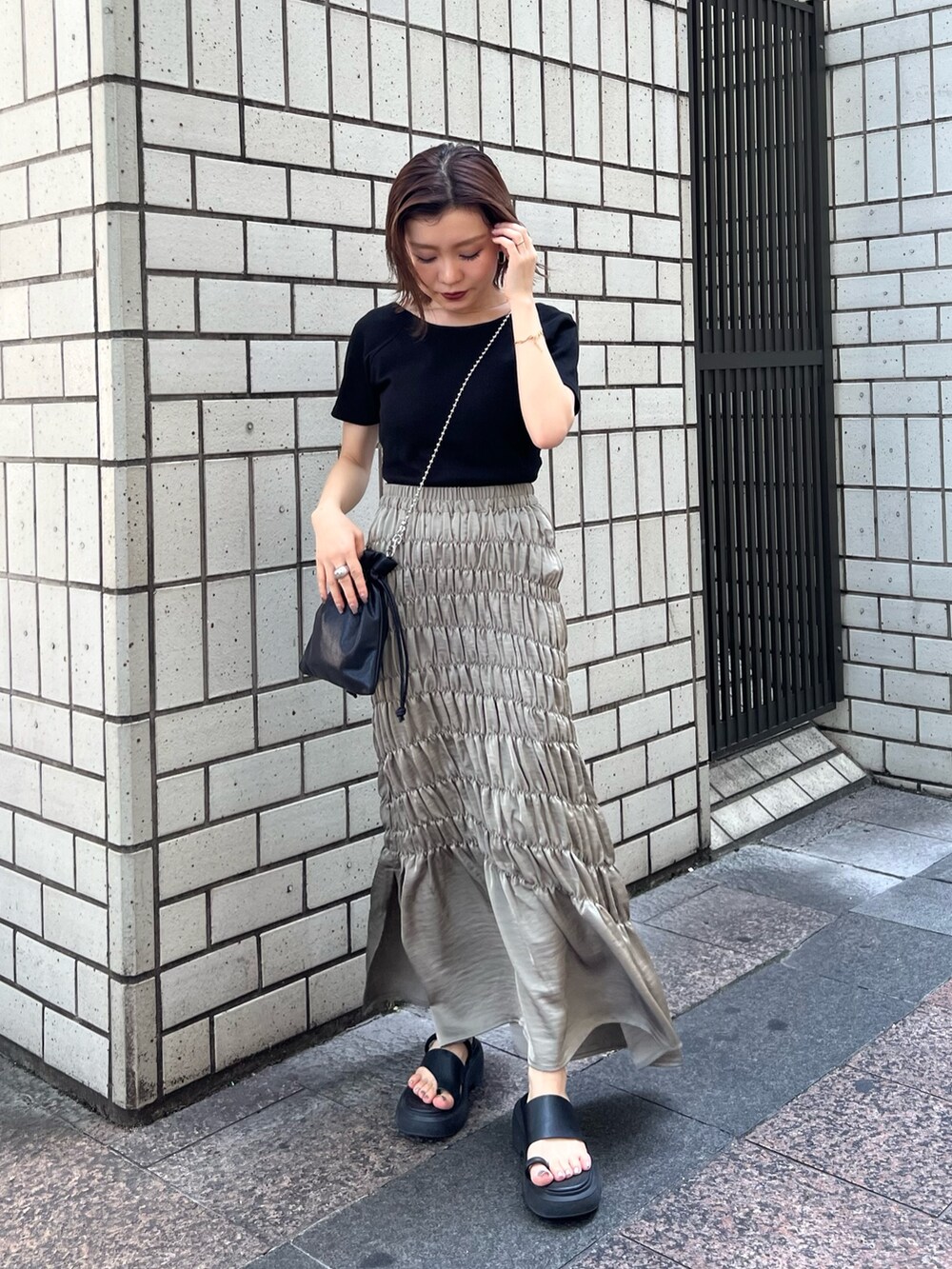 ブラック系のTシャツ/カットソー、グリーン系のスカート、ブラック系のショルダーバッグを着用したレディースの夏コーディネートの2枚目の写真