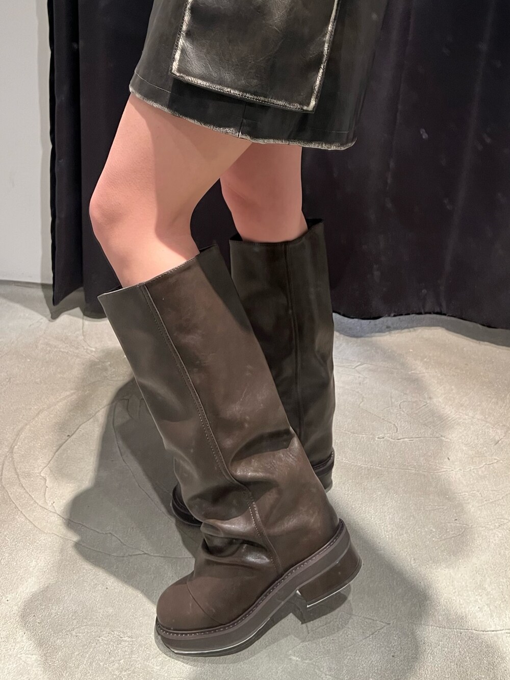 グレー系のニット/セーター、ブラウン系のブーツ、ブラウン系のスカートを着用したレディースの冬コーディネートの7枚目の写真