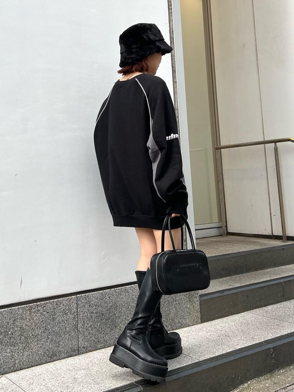 ブラック系のスウェット、ブラック系のブーツ、ブラック系のハットを着用したレディースの秋コーディネートの2枚目の写真