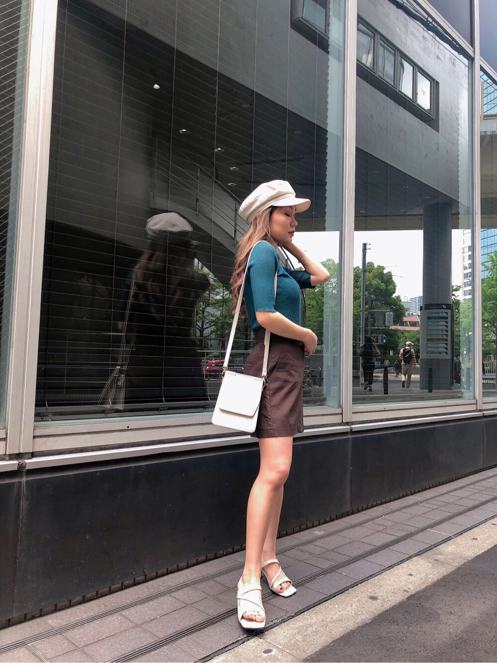 ホワイト系のハンドバッグ、ホワイト系のサンダル、グリーン系のニット/セーターを着用したレディースの夏コーディネートの2枚目の写真