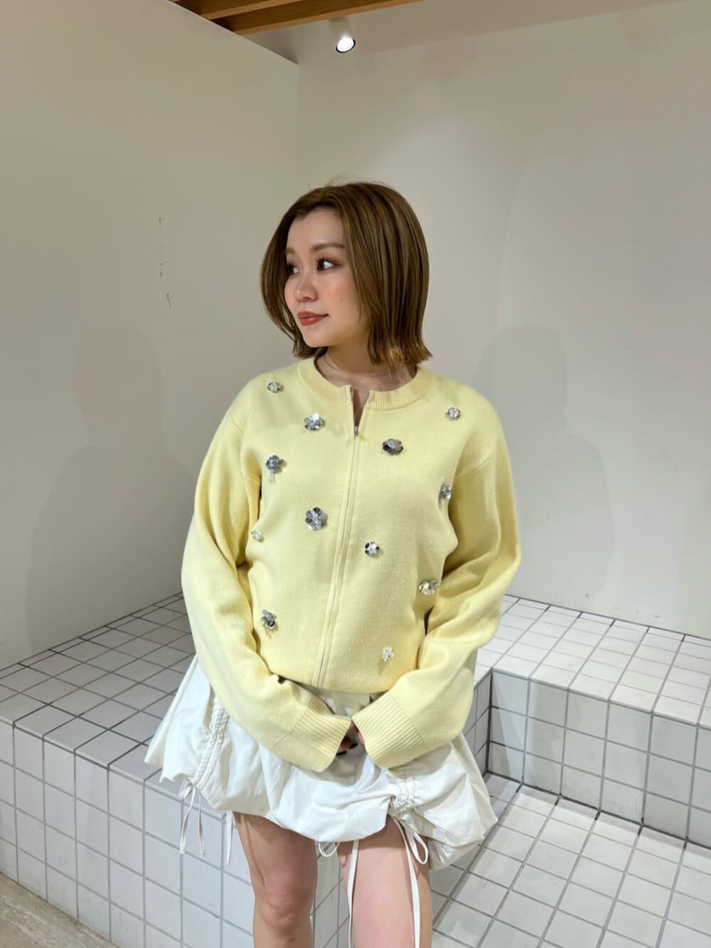 イエロー系のカーディガン/ボレロ、ホワイト系のスカートを着用したレディースの冬コーディネートの4枚目の写真