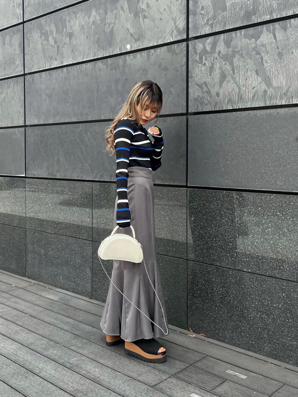 ブルー系のポロシャツ、グレー系のスカート、ブラック系のブーツを着用したレディースの春コーディネートの3枚目の写真