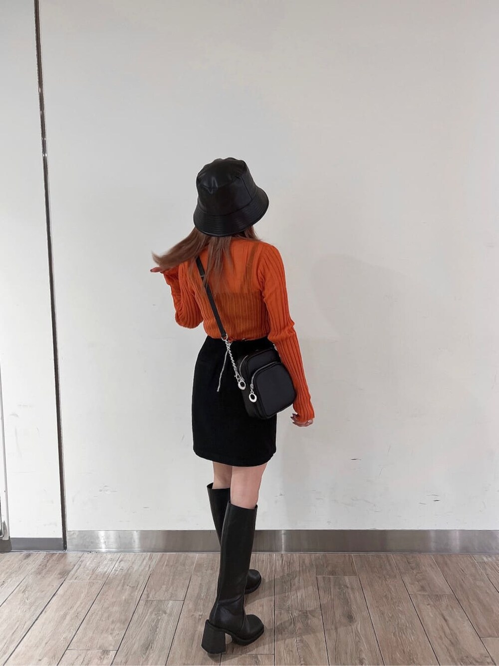 ブラック系のブーツ、オレンジ系のニット/セーター、ブラック系のスカートを着用したレディースの秋コーディネートの3枚目の写真