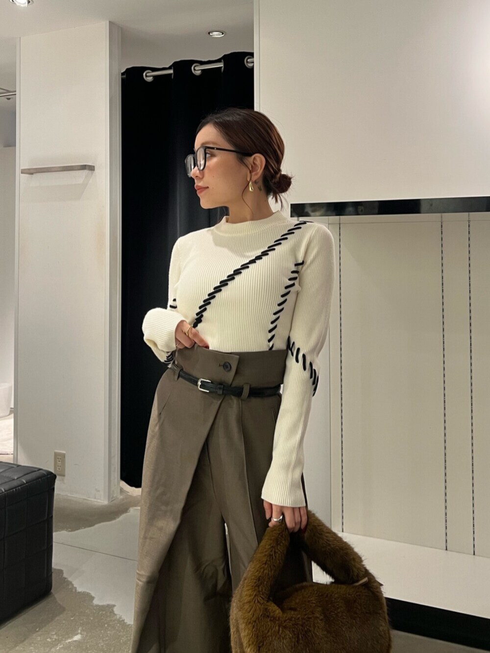 ホワイト系のニット/セーター、ブラック系のブーツ、ブラウン系のハンドバッグを着用したレディースの秋コーディネートの5枚目の写真