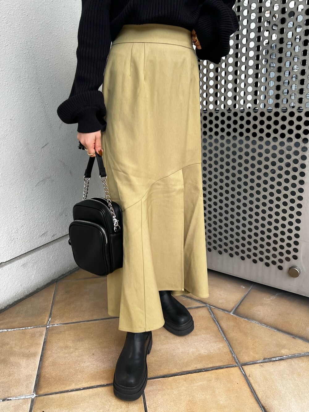 グリーン系のスカート、ブラック系のニット/セーター、ブラック系のショルダーバッグを着用したレディースの冬コーディネートの7枚目の写真