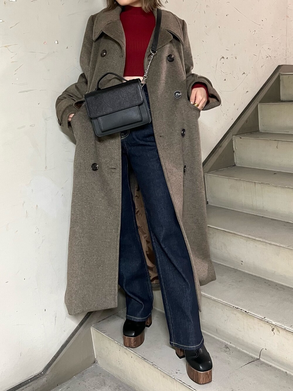 ブルー系のデニムパンツ、ブラウン系のチェスターコート、レッド系のニット/セーターを着用したレディースの秋コーディネートの5枚目の写真