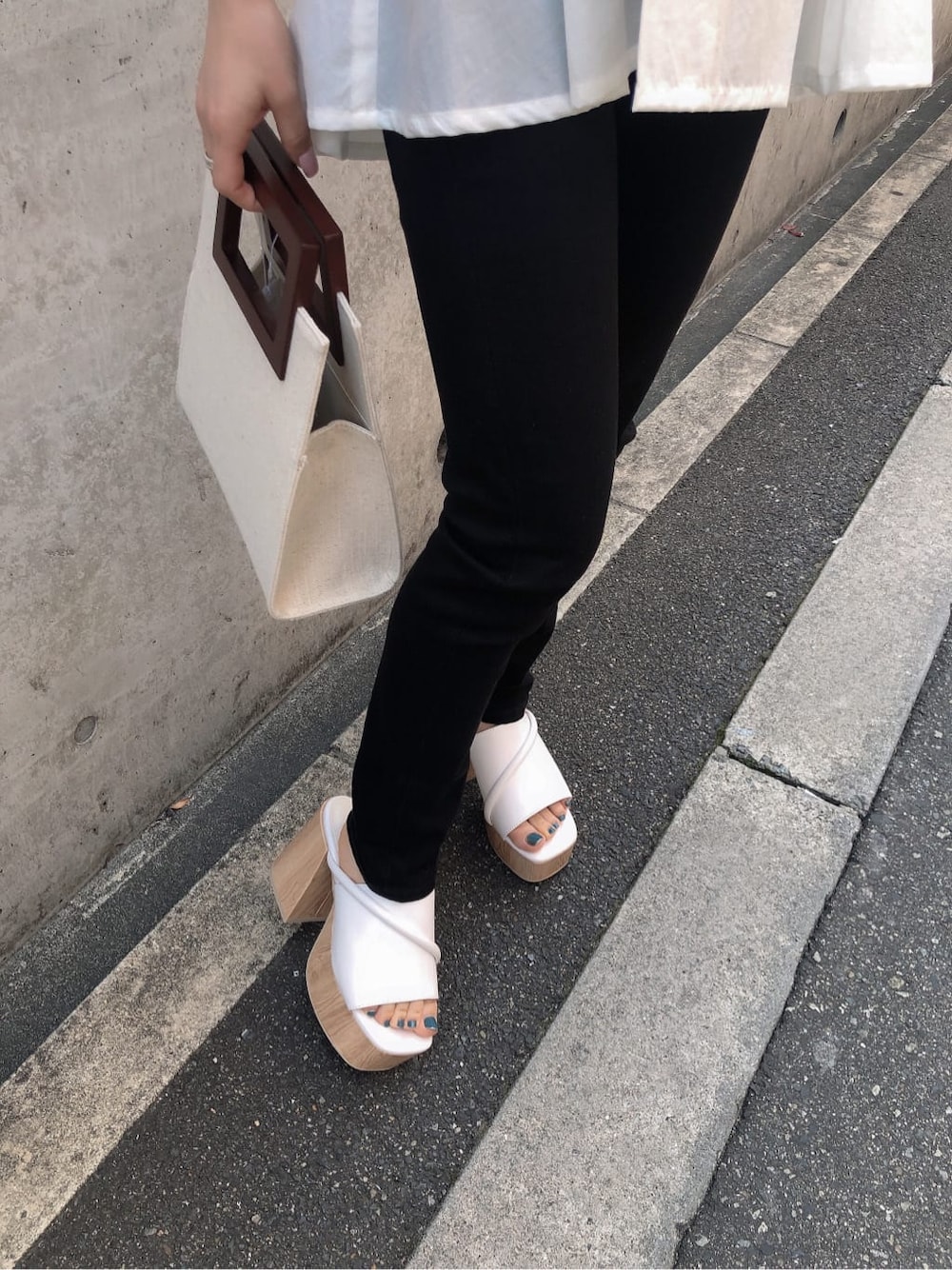 ホワイト系のサンダル、ブラック系のデニムパンツ、ホワイト系のハンドバッグを着用したレディースの春コーディネートの9枚目の写真