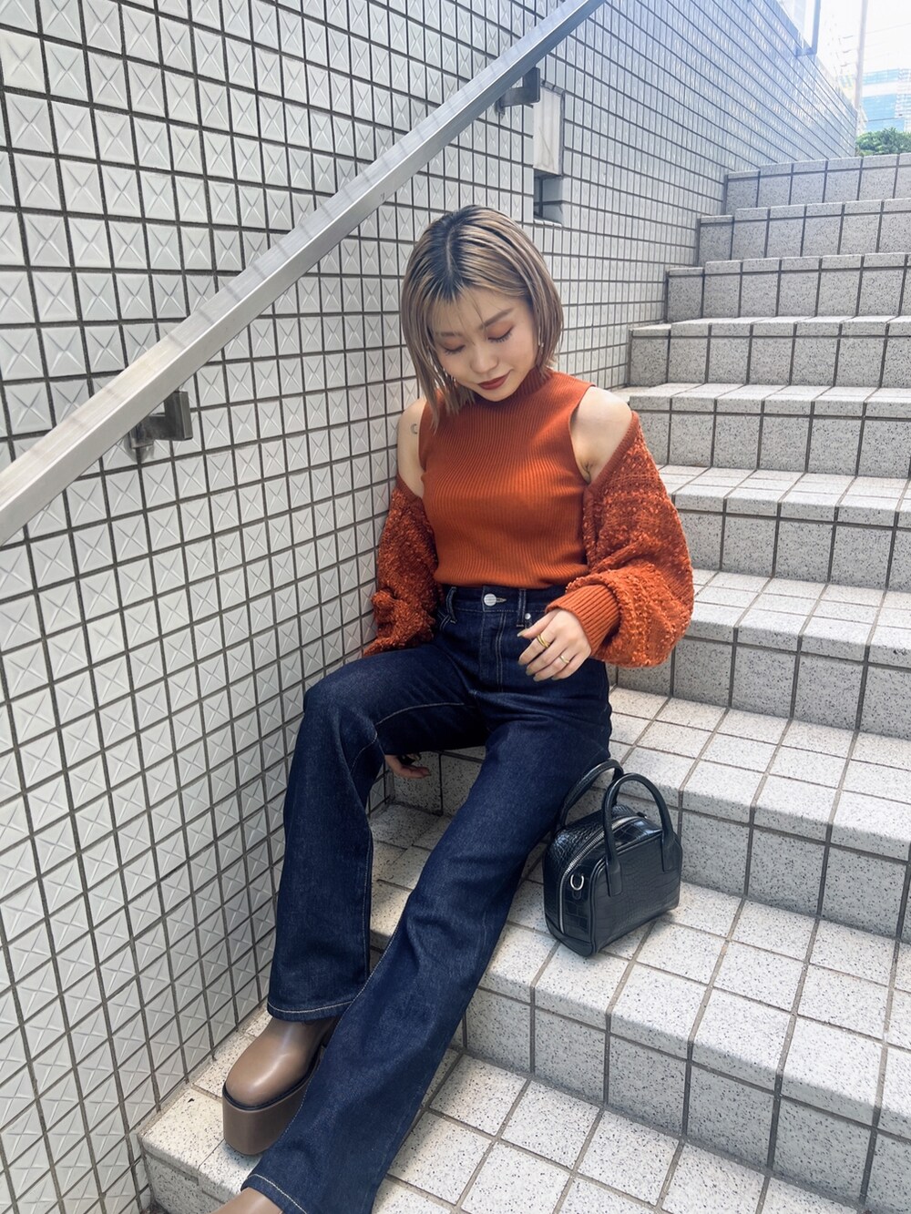 オレンジ系のカーディガン/ボレロ、ブルー系のデニムパンツ、ブラウン系のブーツを着用したレディースの夏コーディネートの2枚目の写真