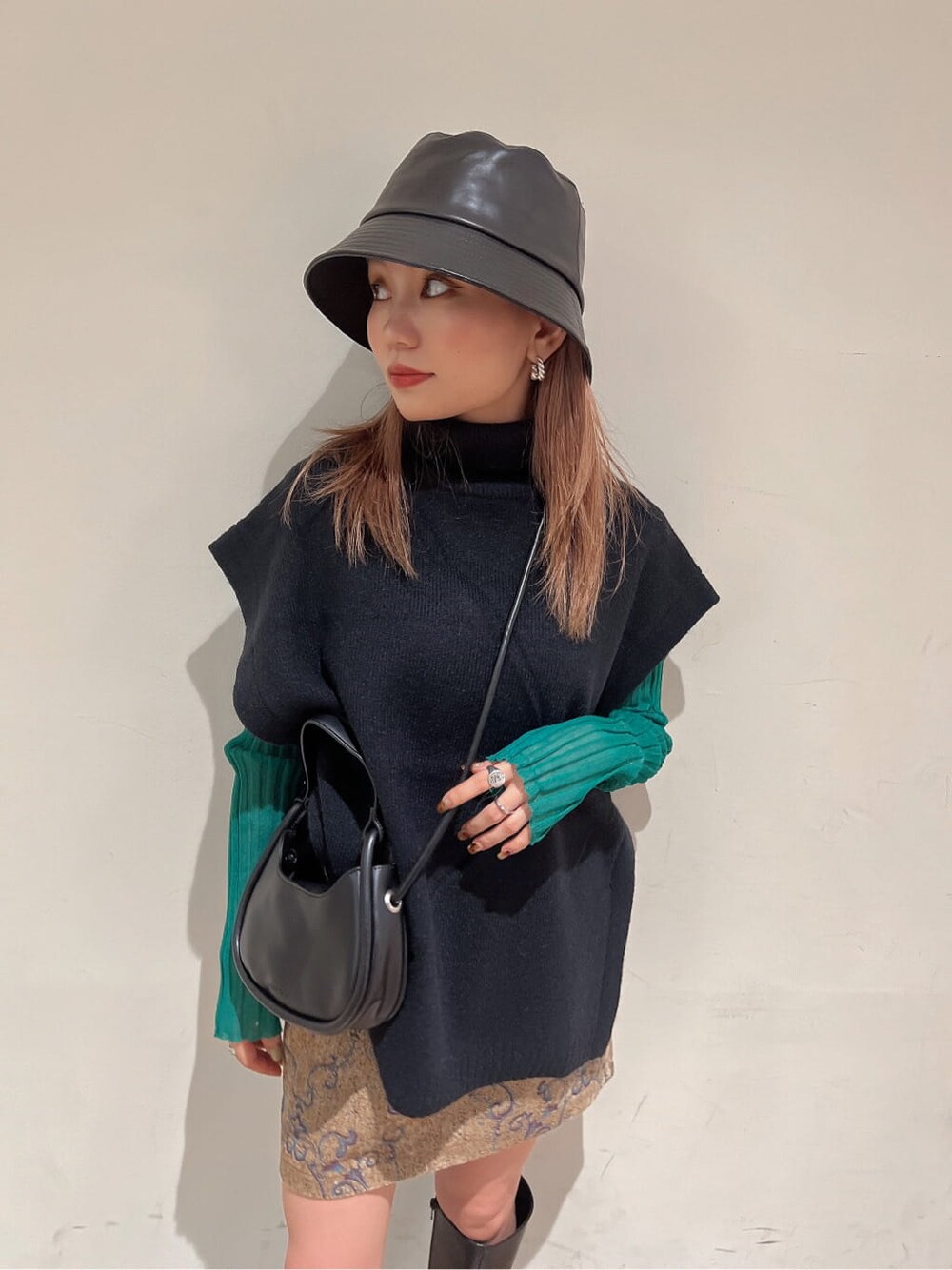 ブラック系のブーツ、グリーン系のニット/セーター、ブラウン系のスカートを着用したレディースの秋コーディネートの4枚目の写真