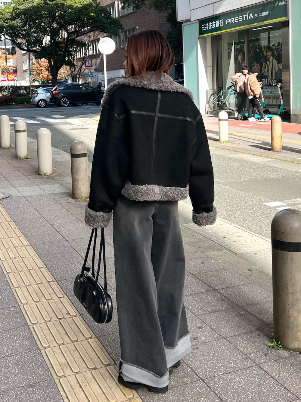 グレー系のデニムパンツ、ブラック系のニット/セーター、ブラック系のブーツを着用したレディースの冬コーディネートの2枚目の写真