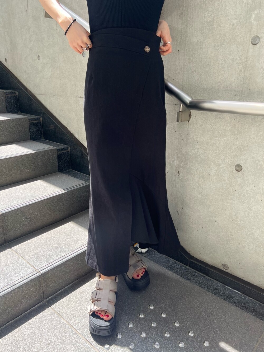 ブラック系のスカート、ブラック系のタンクトップ、ブラウン系のサンダルを着用したレディースの春コーディネートの7枚目の写真