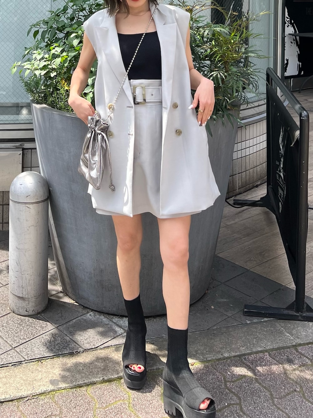 グレー系のベスト、ブラック系のブーツ、グレー系のスカートを着用したレディースの春コーディネートの6枚目の写真