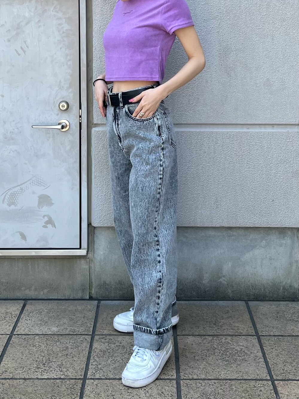 グレー系のデニムパンツ、パープル系のTシャツ/カットソー、ブラック系のベルトを着用したレディースの春コーディネートの6枚目の写真