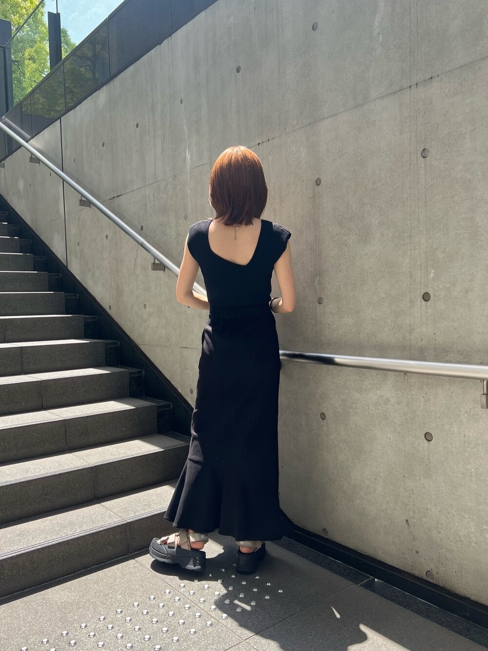 ブラック系のスカート、ブラック系のタンクトップ、ブラウン系のサンダルを着用したレディースの春コーディネートの3枚目の写真