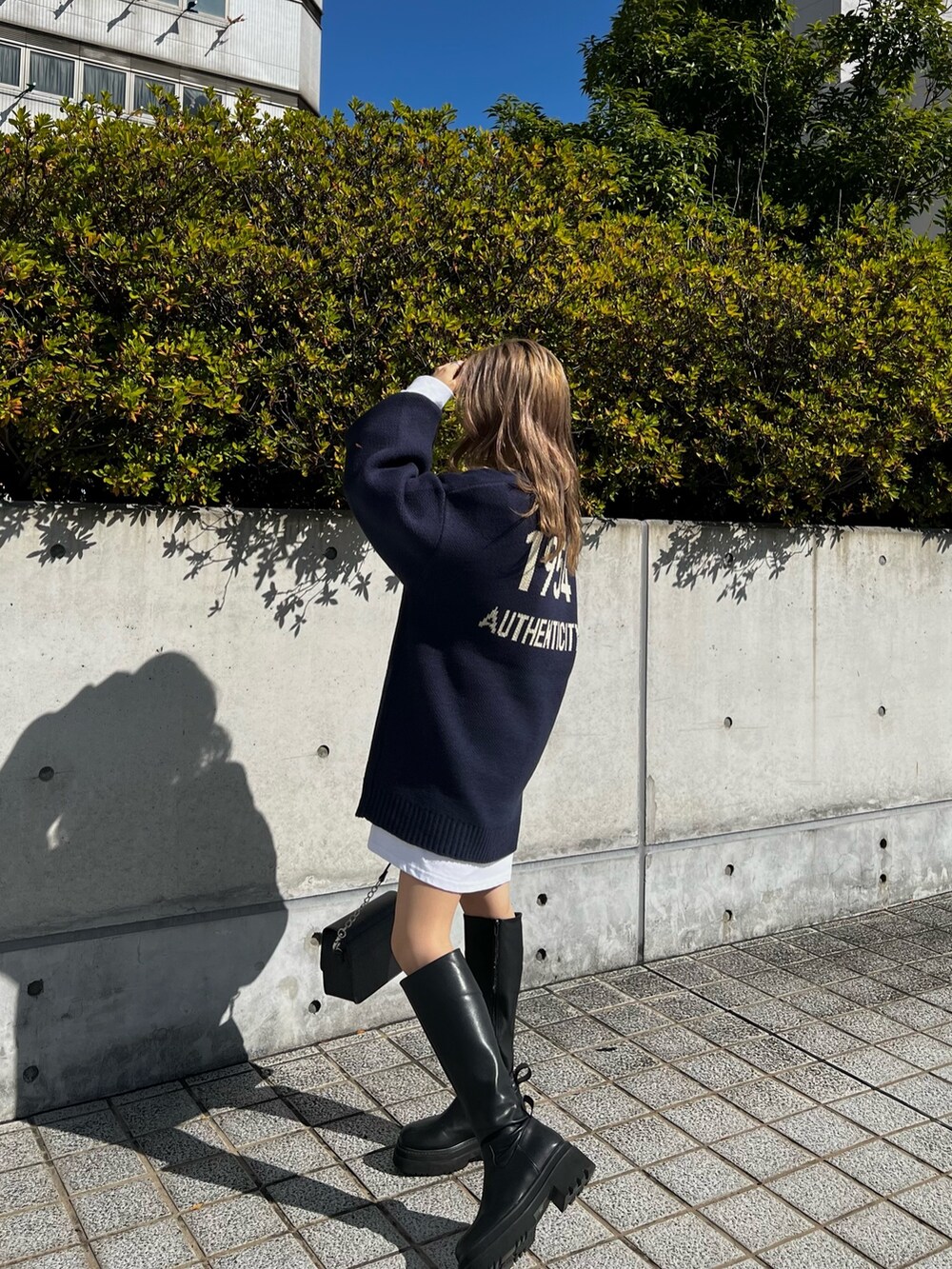 ブラック系のブーツ、ブラック系のショルダーバッグ、ホワイト系のTシャツ/カットソーを着用したレディースの秋コーディネートの3枚目の写真