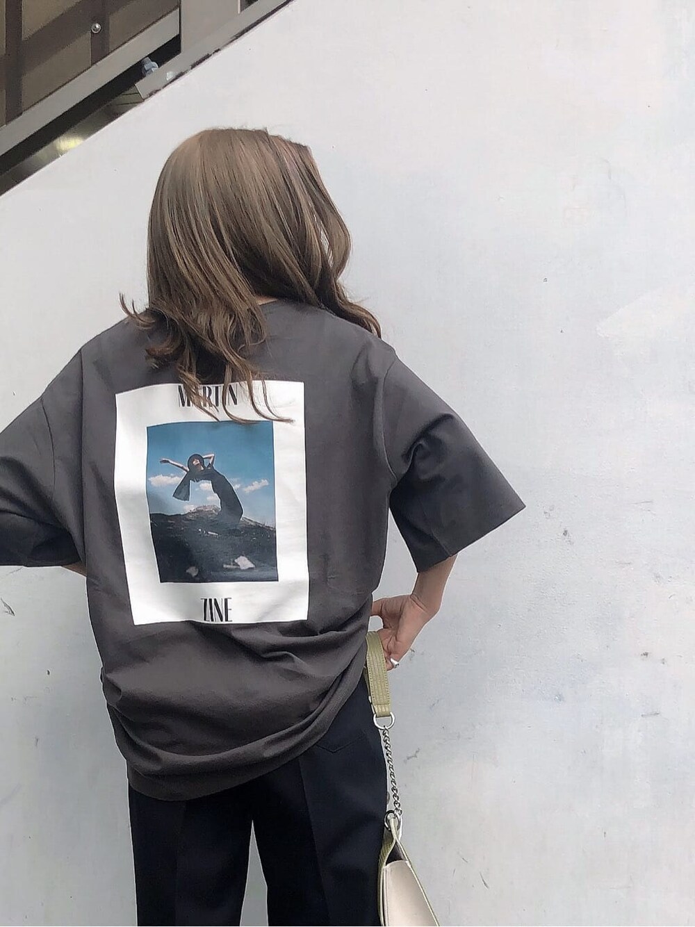 ブラック系のスラックス、ホワイト系のハンドバッグ、グレー系のTシャツ/カットソーを着用したレディースの春コーディネートの6枚目の写真