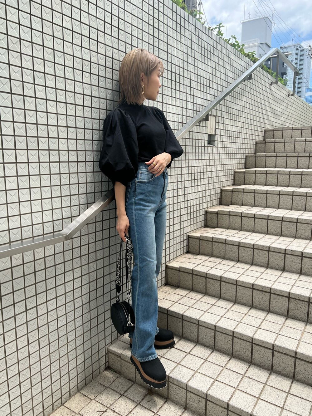 ブルー系のデニムパンツ、ブラック系のTシャツ/カットソー、ブラック系のショルダーバッグを着用したレディースの夏コーディネートの3枚目の写真