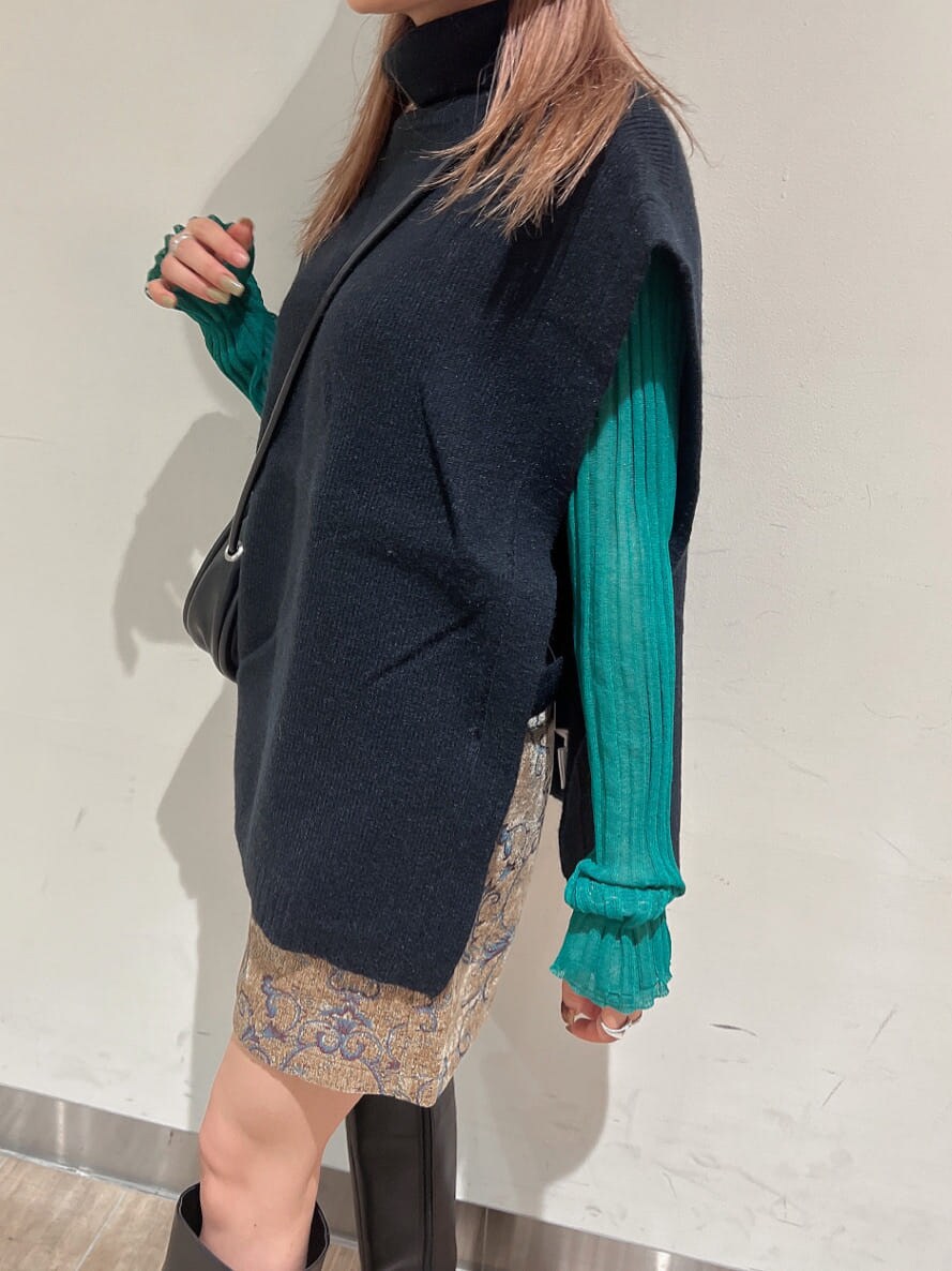 ブラック系のブーツ、グリーン系のニット/セーター、ブラウン系のスカートを着用したレディースの秋コーディネートの3枚目の写真