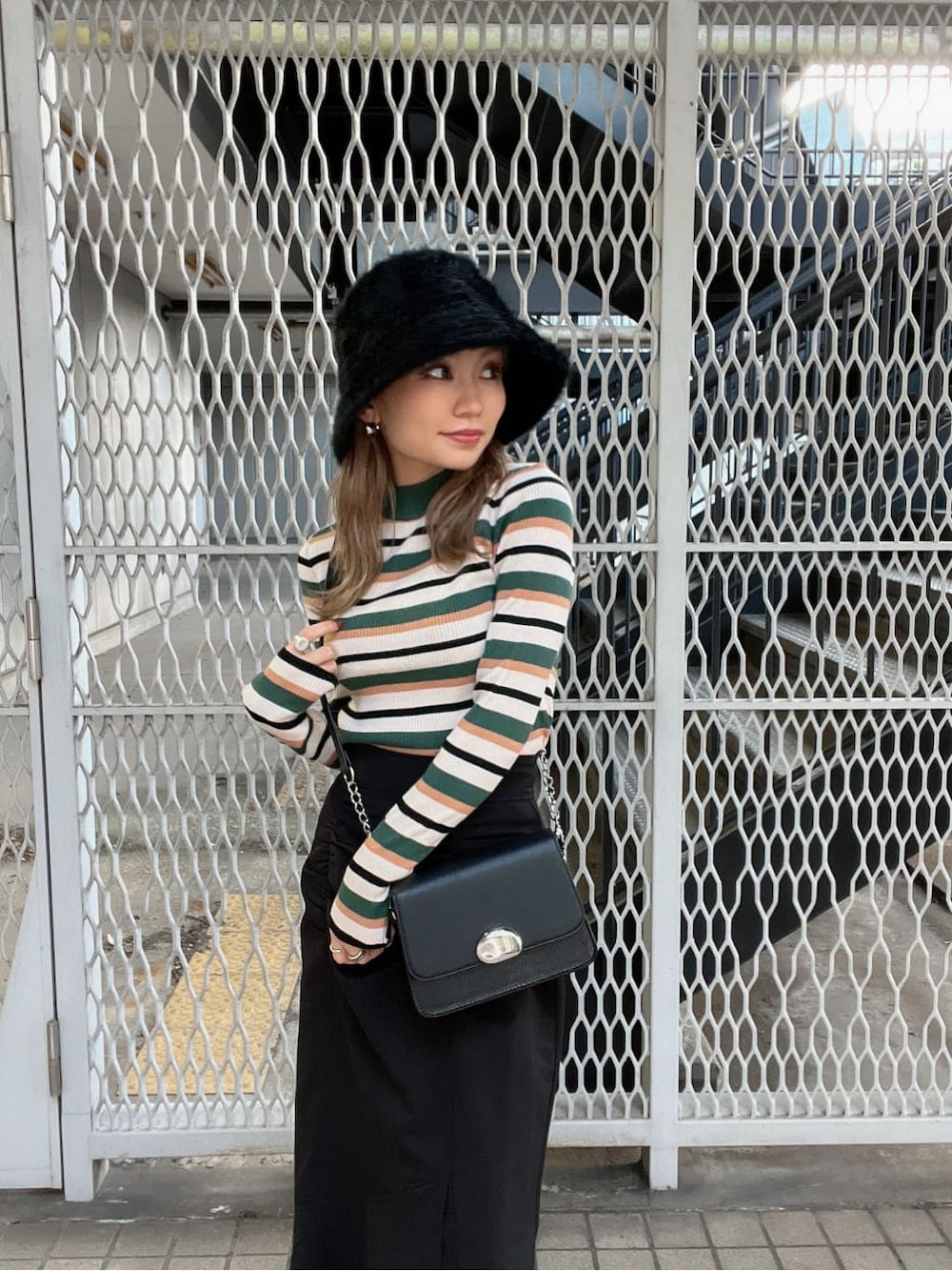 ブラック系のブーツ、ブラック系のショルダーバッグ、ブラック系のスカートを着用したレディースの秋コーディネートの5枚目の写真