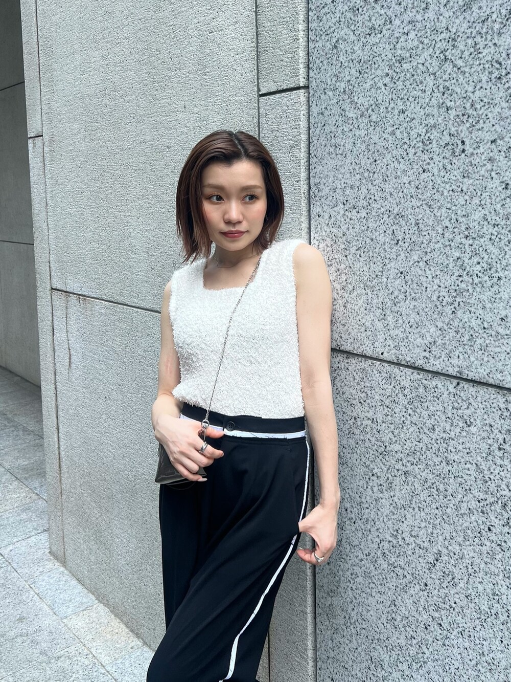 ホワイト系のニット/セーター、ブラック系のその他パンツ、ゴールド系のショルダーバッグを着用したレディースの夏コーディネートの5枚目の写真