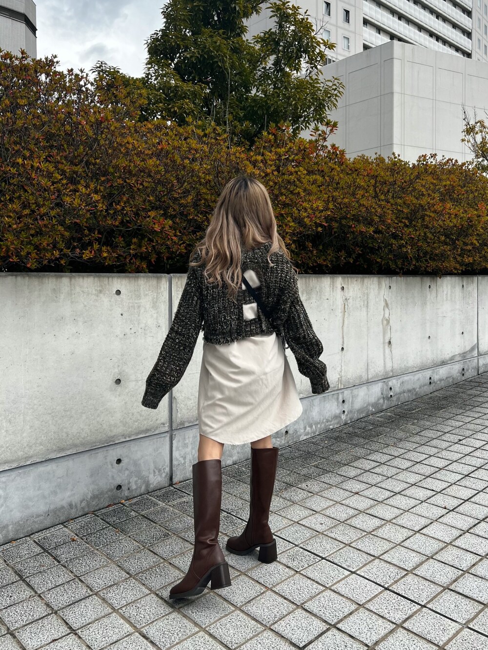 グリーン系のワンピース、ブラック系のショルダーバッグ、ブラウン系のブーツを着用したレディースの冬コーディネートの3枚目の写真