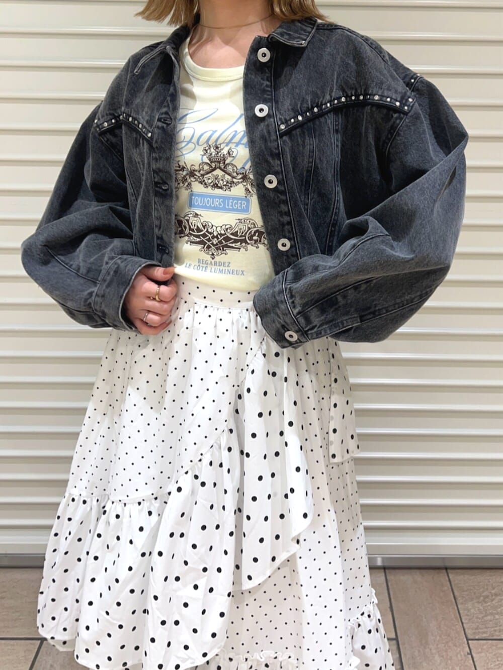 イエロー系のTシャツ/カットソー、ブラック系のデニムジャケット、ホワイト系のスカートを着用したレディースの春コーディネートの5枚目の写真